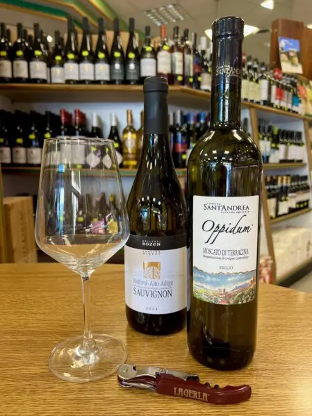 Bottiglie di Sauvignon e Moscato di Terracina in primo piano con selezione di vini bianchi italiani presso La Sorgente dell’Alimentazione D'Onofrio a Roma.